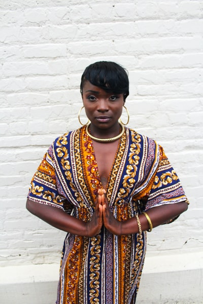 一位非洲裔美国妇女戴着环形耳环，双手合十祈祷。